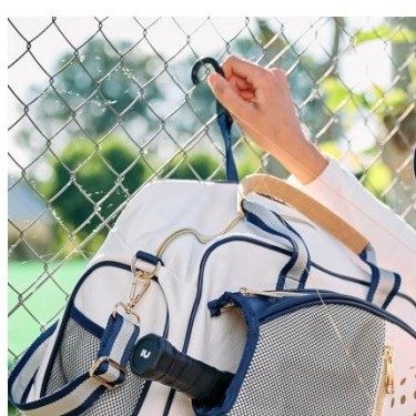 Pickleball duffel hanging on a court fence by its built-in hook
